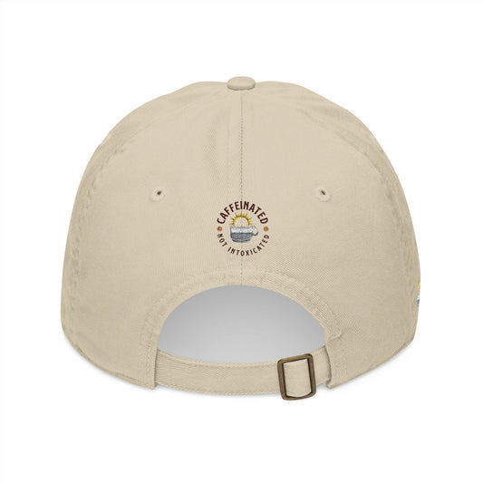 Back profile of beige cap showing circular 'Caffeinated Not Intoxicated' embroidered logo with coffee cup and sunrise graphic, adjustable buckle strap